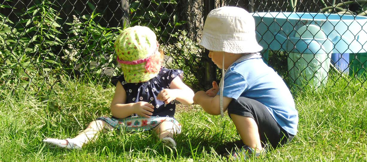 Two children playing outside in grass